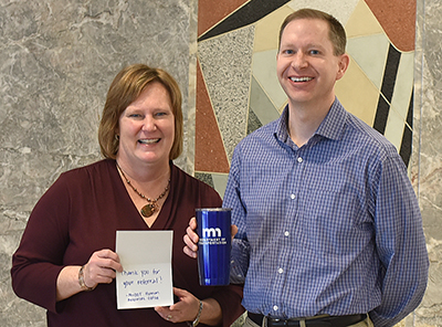 Photo: a woman standing next to a man, who is holding a MnDOT mug